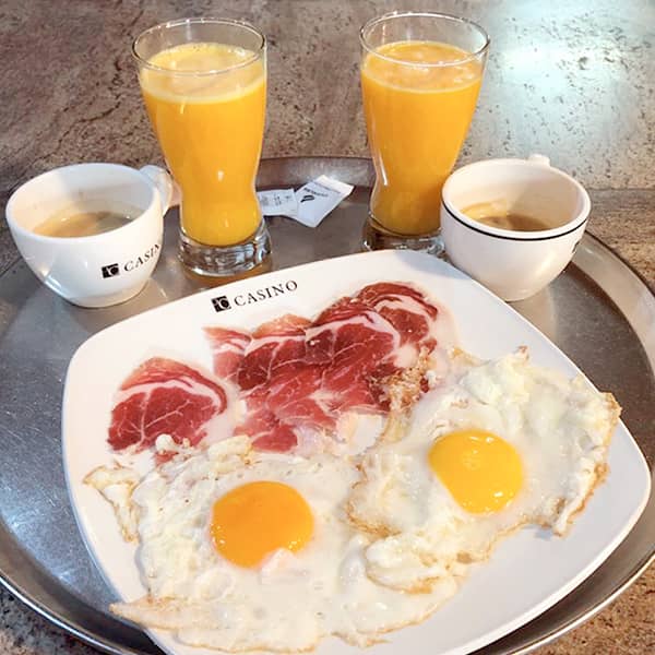 Desayuno, huevos fritos con jamón, café y zumo de naranja